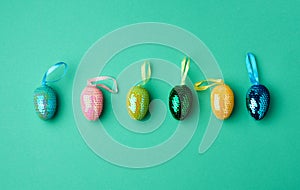 Multicolored decorative Easter eggs decorated with sequins on a green background