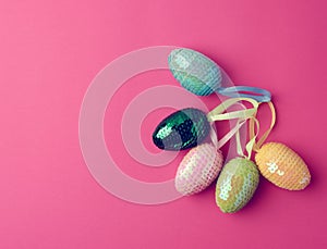 Multicolored decorative Easter eggs decorated with sequins on a pink background