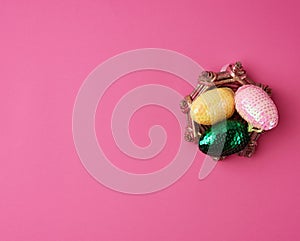 Multicolored decorative Easter eggs decorated with sequins on a pink background