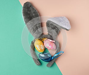 Multicolored decorative Easter eggs decorated with sequins and rabbit mask on the head with ears