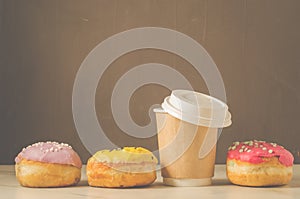 multicolored donuts in glaze and a paper coffee cup/multicolored donuts in glaze and a paper coffee cup on a background with copy