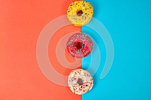 Multicolored donuts on a pink and blue background, space for text