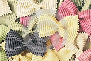 Multicolored dried raw colored organic pasta, farfalle. Different kinds natural tastes and additives. Top view.