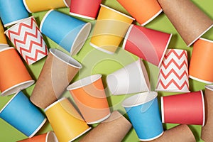Multicolored eco paper party cups on green background
