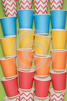 Multicolored eco paper party cups on green background