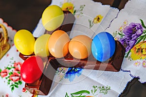 Multicolored eggs decorated for Easter holiday. Row of colorful Easter eggs on rustic wood cross and wooden table. Top view of