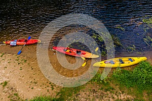 Multicolored empty kayaks on the river bank, view from above