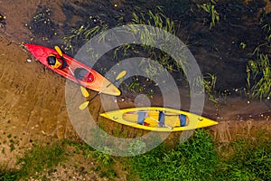 Multicolored empty kayaks on the river bank, view from above