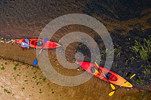 Multicolored empty kayaks on the river bank, view from above