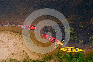 Multicolored empty kayaks on the river bank, view from above