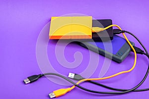 Multicolored external portable hard disk drives isolated on violet