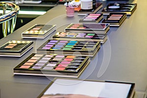 Multicolored eyeshadow, mascara, lipstick, facial cosmetics on the shop counter in the mall photo