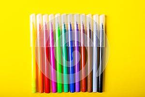 Multicolored felt-tip pens on bright yellow background
