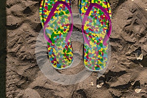 Multicolored flip flops on sand with drawn heart shape. Consept of vacation