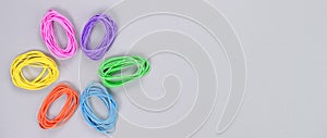 Multicolored flower made of elastic. Top view of colorful rubber bands isolated on grey. Rainbow elastic rubber bands on white.