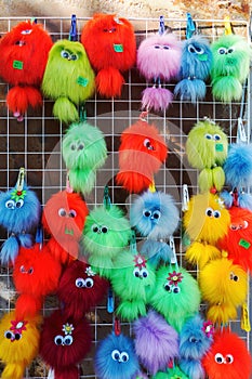 Multicolored fluffy keychains with eyes hanging on a grid outdoors photo