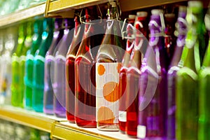 Multicolored glass bottles on the shelf in the store.