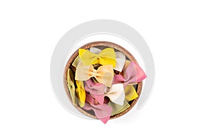 Multicolored green yellow and red bowtie pasta in a wooden bowl isolated over white top down