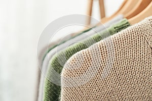 Multicolored handknitted sweaters on hangers