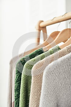 Multicolored handknitted sweaters on hangers