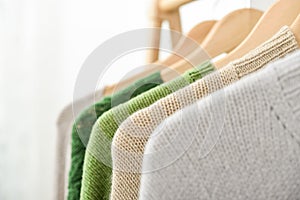 Multicolored handknitted sweaters on hangers