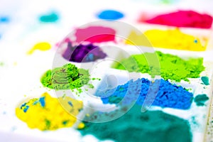 Multicolored holi paints in a palette on a white background