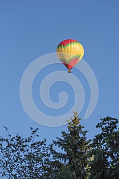 Multicolored hot air balloon flies in the blue sky