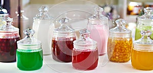 Multicolored jars with jam on shelf