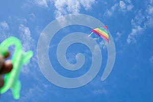 Multicolored kite on the background of the blue sky with clouds