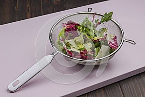 Multicolored leafy vegetable mix in metal colander. Vegan food