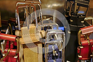 Multicolored leather belts on hangers close-up in the fashion store. Personal accessories. Stylish outfit