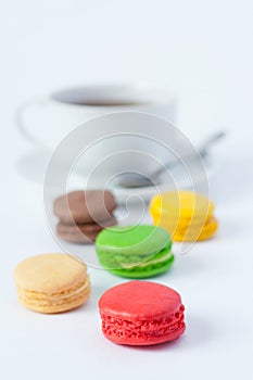 Multicolored macarons in the foreground and a cup of tea