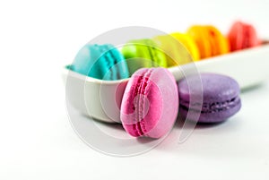 Multicolored macarons isolated on a white floor and housed in white ceramic vessels, selective focus