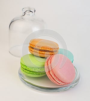 Multicolored macaroon pastry biscuits in a glass case on white. Sweet dessert french macarons baked goods. decoration for tea