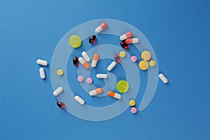Multicolored medical pills of various shapes on a blue background