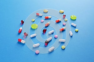 Multicolored medical pills of various shapes on a blue background