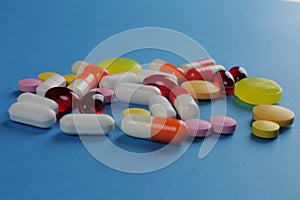 Multicolored medical pills of various shapes on a blue background