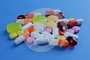 Multicolored medical pills of various shapes on a blue background