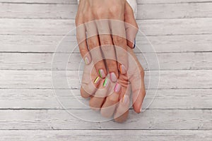 Multicolored modern manicure, nail design. Summer mood, on wooden background. Top view