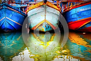 Multicolored old boat in the fishing port. Colored reflections in the water. Sri Lanka. Tangalle.