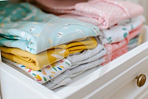 multicolored onesies folded in a nursery drawer