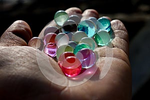 Multicolored Orbeez, expanding colorful jelly water balls on hand palm.