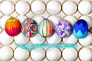 Multicolored painted easter eggs on white in tray, food photography