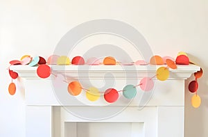 Multicolored paper circle garland adorning a white mantel, creating a cheerful and festive decoration for parties or photo