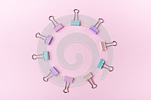 Multicolored paper clips in circle form on pink background Back to school concept with copy space for text