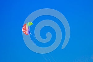 Multicolored parachute in the blue sky