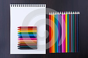 Multicolored pencils, crayons and a paper notepad