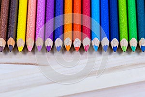 Multicolored pencils with water drops on wooden table