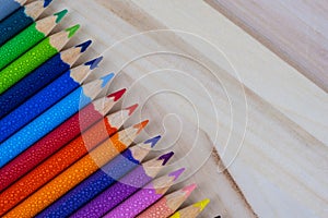 Multicolored pencils with water drops on wooden table