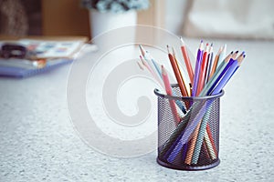 Multicolored pensils in the box on a desk